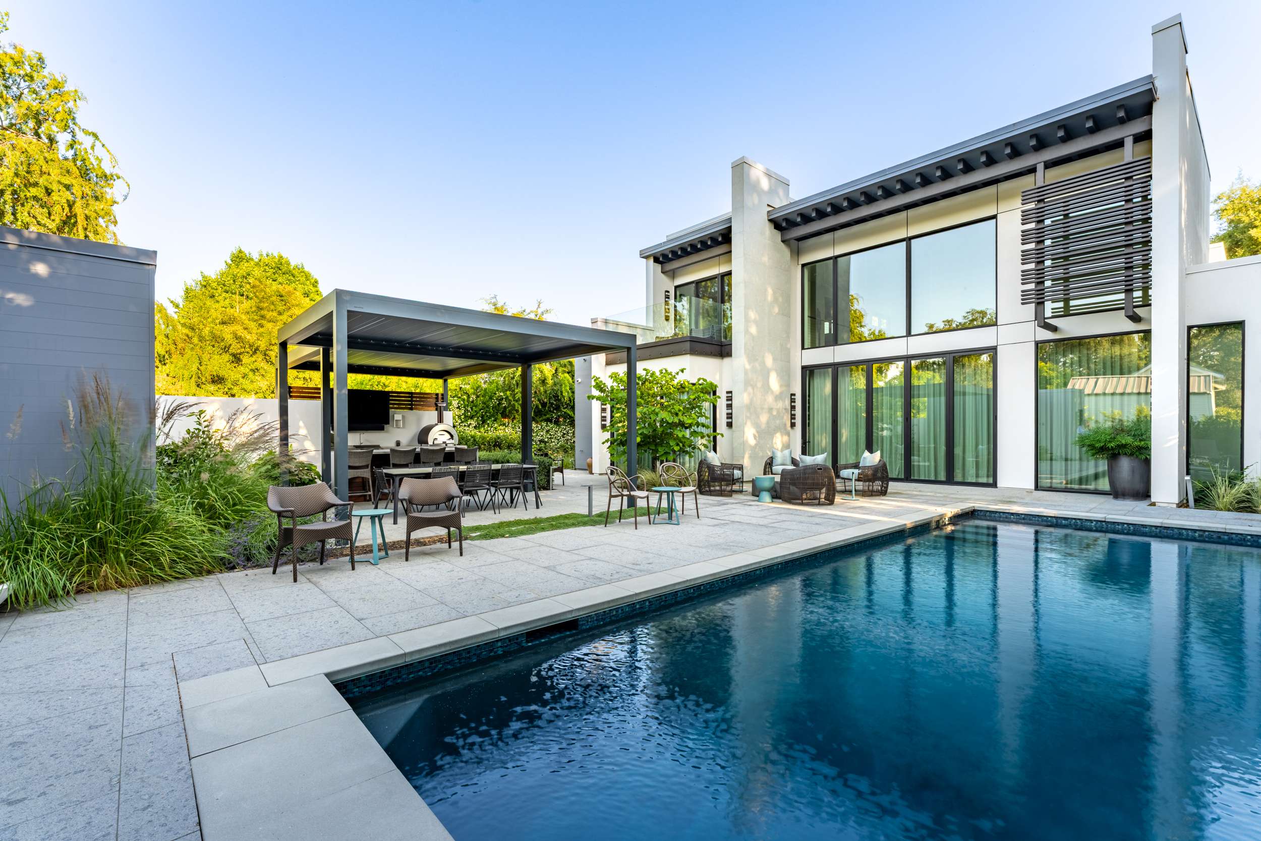Modern home, pool, pergola, and ornamental grasses in a contemporary backyard